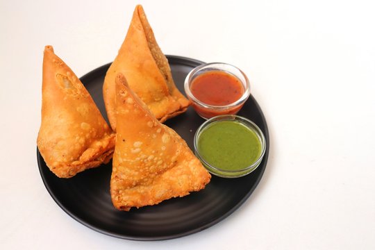 Vegetarian Aloo samosa or samosas. Indian special traditional street food. Famous Indian Punjabi samosa filled with spicy boiled potato mixture. served with green and red chutneys. Copy space.