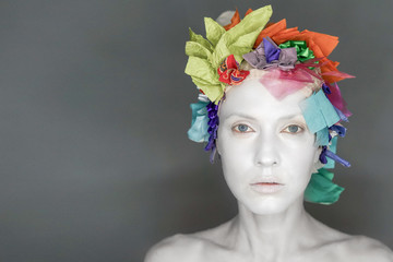 Exotic unusual white clay face woman makeup with floral headwear