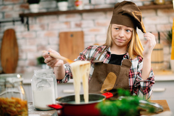 Little girl in kitchen. Cute girl cooking spaghetti 