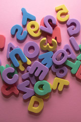 Colorful plastic alphabet letters on pink background, top view