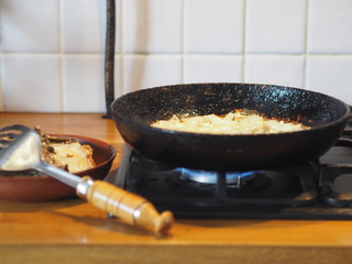 Home cooking. Fried onions in oil in a black pan on the stove. Nearby fried fish. The stage of preparation of the filling for the pie.