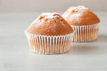 Fresh homemade delicious muffins are taken out of the oven and they cool on the kitchen table. Muffins sprinkled with sugar. Sweet dessert.