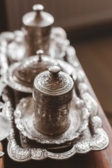 Vertical closeup shot of an antique silver tea set with a blurry background