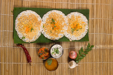 Thick spongy dosas served together with coconut chutney and sambhar on banana leaf
