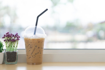 Closeup glass of ice coffee with flower pot in the coffee shop