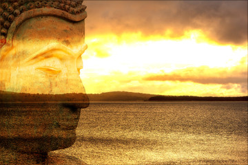 Figure of a Buddha with a lake at sunrise in the background
