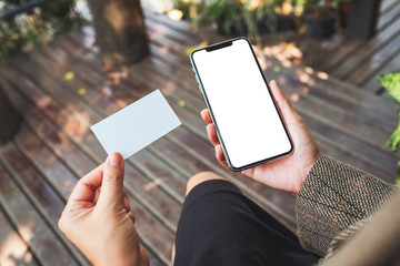 Mockup image of a woman holding white mobile phone with blank desktop screen and a white empty business card