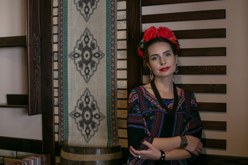 horizontal photo of a young woman in mexican national dress who stands thoughtfully looking at the camera