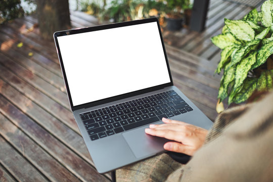 Mockup image of a woman using and touching on laptop touchpad with blank white desktop screen in the outdoors