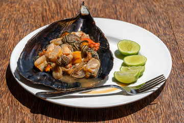 Raw clam meat in a large seashell served for food at a local restaurant on the island of Zanzibar, Tanzania, East Africa