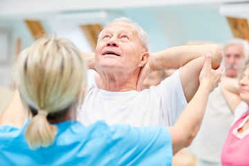 Obraz premium Trainer supervises senior in back exercises