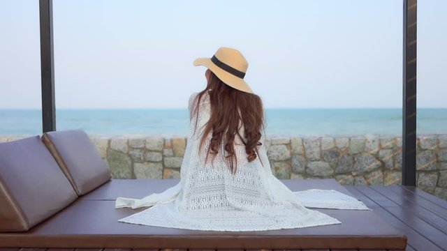 Young beautiful women sitting and relaxing on the beachside resort with a beautiful view of the endless ocean.