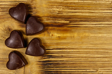 Heart shaped chocolate candies on wooden background. Top view, copy space. Valentine Day concept
