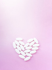 Obraz na płótnie Canvas Heart shape made from pills for therapy, concept of treatment and health care on pink