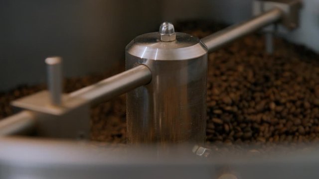 Selective focus shot of roasting machine drum, spin around and move coffee beans for perfect roast. Coffee roasting process in small business company