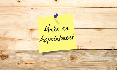  Yellow paper note with text Make an Appointment  on wooden background