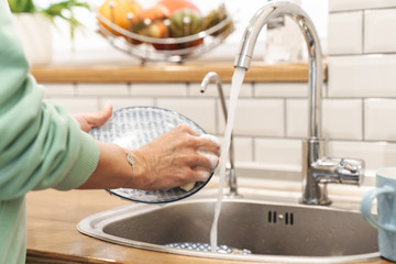 Woman indoors at home wash the dishes at the kitchen.