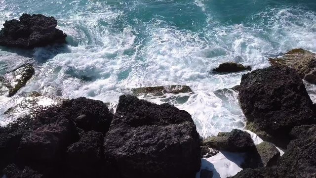 Rough waves crashing the rock shore of slugs bay in Malta, low drone flyover