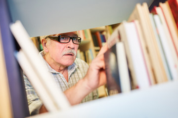 Senior man is looking for books in the library