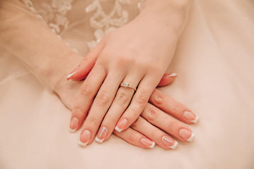 hands of a young girl with beautiful manicure lie on a dress