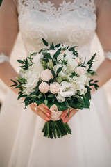 wedding bouquet with various white flowers in the hands of the bride
