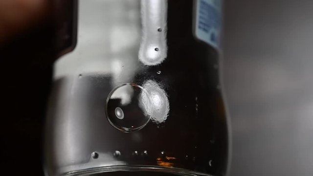 Water bubbles moving in a glass bottle, slow motion