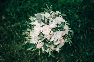 wedding bouquet of white roses lies on the green grass