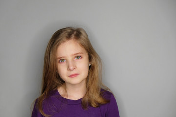 Close-up studio portrait of unhappy beautiful little girl with tears.
