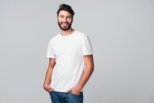 Handsome young man smiling isolated on grey background wearing casual t-shirt and jeans