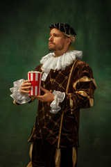 Get ready for cinema. Portrait of medieval young man in vintage clothing standing on dark...