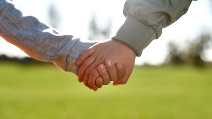 Friendship. Close up photo of two kids holding hands while spending time in the park