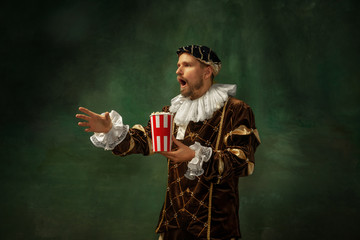 Emotional watching soccer. Portrait of medieval young man in vintage clothing standing on dark...