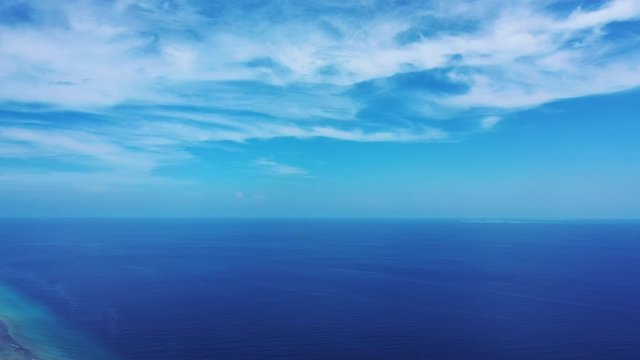 Peaceful blue seascape with deep endless ocean under bright sky with overhanging white clouds in Caribbean
