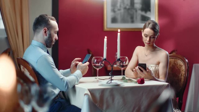 Couple chatting use smartphone during boring romantic date. Medium shot on RED camera