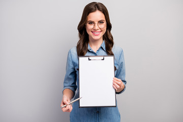 Here. Photo of beautiful wavy business lady hold clipboard showing contract space for signing up details wear specs casual jeans denim shirt isolated grey color background - obrazy, fototapety, plakaty
