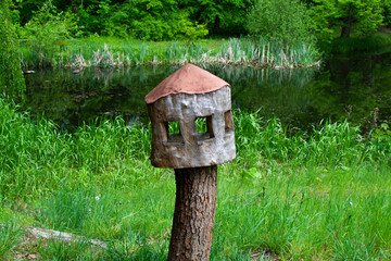 Wooden nest box for birds made with a tree trunk in a green forest