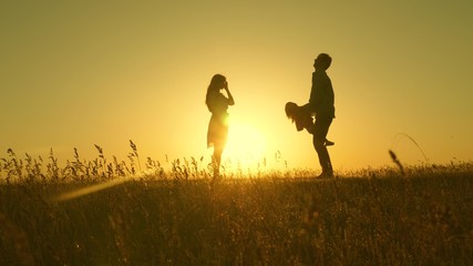child, dad and mom play in meadow in the sun. concept of a happy childhood. mother, father and little daughter walking in a field in the sun. Happy young family. concept of a happy family.