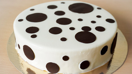 White glazed birthday cake with few dark chocolate rounds on it. 