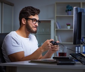 Young man playing games long hours late in the office