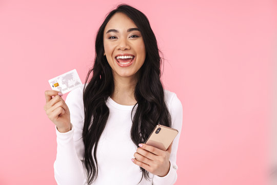 Image of young brunette asian woman holding cellphone and credit card