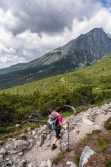 Fototapeta na wymiar Young woman on a mountain terrain trail. Hiking in High Tatras National Park, Slovakia.