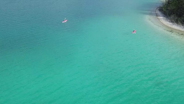 People Enjoy Kayaking In the Lake With Small Island Full Of Pine Trees In Boya Lake, British Columbia Canada - Aerial shot