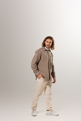 handsome man in shirt and trousers looking away on grey background