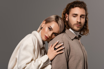 woman in white coat hugging handsome man in shirt isolated on grey