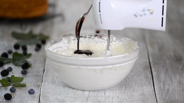 Pastry chef adding berry puree into buttercream. Beat With A Mixer Berry Cream.