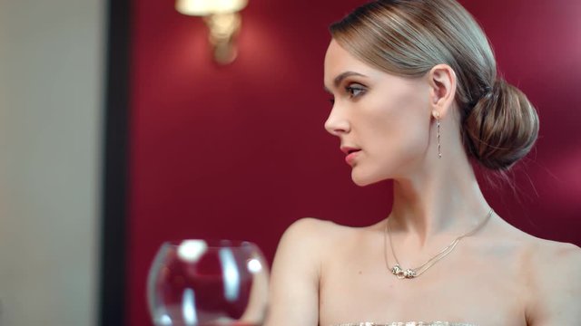 Fashionable woman posing with bocal of wine at restaurant. Medium close up shot on 4k RED camera
