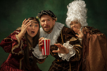 Emotional horror. Portrait of medieval young people in vintage clothing on dark background. Models...
