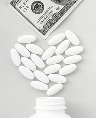 Heart made of pills and money over the neck of a bottle. Paid medical service, bribe in pharmaceutical company on gray background