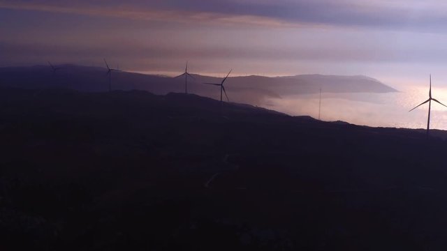 Silhouette of wind turbines rotating. Aerial, tilt up