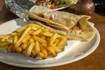 Kebab and French fries recipe on a white dish table in an European country.